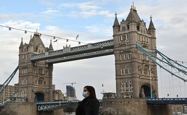 Un peatón que lleva una máscara debido a la pandemia de coronavirus pasa por el Tower Bridge en Londres mientras Inglaterra se prepara para entrar en un segundo confinamiento. AFP