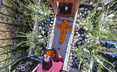 Una mujer decora la tumba de un familiar con caléndulas mexicanas formando una cruz en el Panteón La Magdalena, en San Pedro Cholula, estado de Puebla, México. AFP