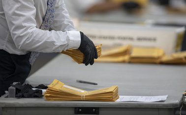Un trabajador del Departamento de Elecciones de Detroit ayuda a clasificar las papeletas de voto en ausencia en la Junta Central de Conteo en el Centro TCF. AFP