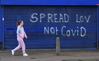Un peatón pasa junto a un graffiti que dice "Spread Lov, not COVID" en las contraventanas de una casa de apuestas cerrada en Hull, en el noreste de Inglaterra. AFP