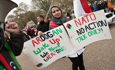 En esta foto de archivo tomada el 9 de abril de 2011, una joven libia sostiene carteles frente a la Casa Blanca en Washington durante una protesta de libios y sirios contra los regímenes de Moamer Kadhafi y Bashar al-Assad. AFP