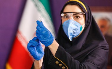 Una trabajadora de la salud prepara una inyección para una mujer durante la primera fase de prueba de una vacuna iraní de fabricación local contra la COVID-19. AFP
