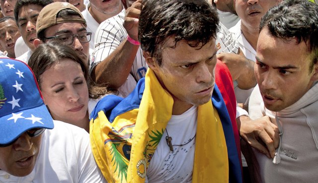 En esta foto del 18 de febrero del 2014, el opositor Leopoldo López, segundo a la derecha, envuelto en una bandera nacional de Venezuela, está flanqueado por José Rafael Pérez, derecha, justo antes de que López se entregara a los guardias nacionales, en Caracas. AFP