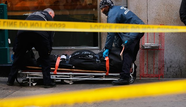 Personal policial saca el cuerpo de la víctima de un andén del metro en la escena del tiroteo. AFP