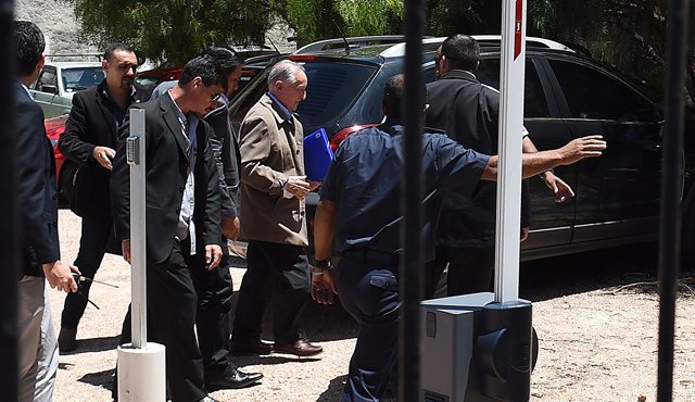 El exvicepresidente de la Fifa, Eugenio Figueredo, (carpeta en mano), es conducido bajo medidas de seguridad para declarar ante la justicia uruguaya por los casos de soborno y corrupción de la Federación Internacional de Fútbol Asociado. AFP