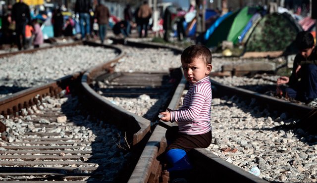 Un niño mira en sentado en las vías del tren en el refugio provicional en la frontera entre Grecia y Macedonia , cerca del pueblo griego de Idomeni , este 5 de marzo de 2016, donde miles de refugiados y migrantes esperan para cruzar la frontera con Macedonia. AFP