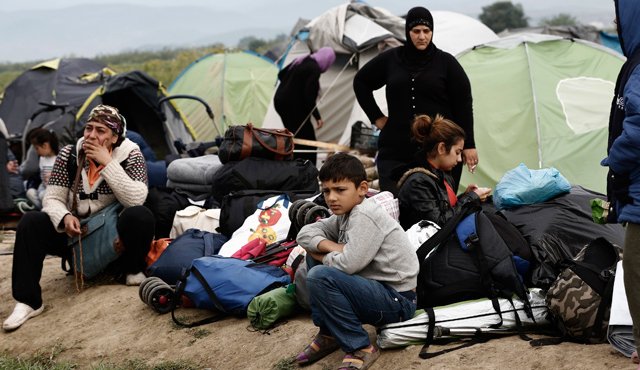 Refugiados y migrantes esperan para embarcar en autocares durante un operativo policial para desmontar un asentamiento improvisado de migrantes en la frontera entre Grecia y Macedonia, en Idomeni, este 24 de mayo. AP