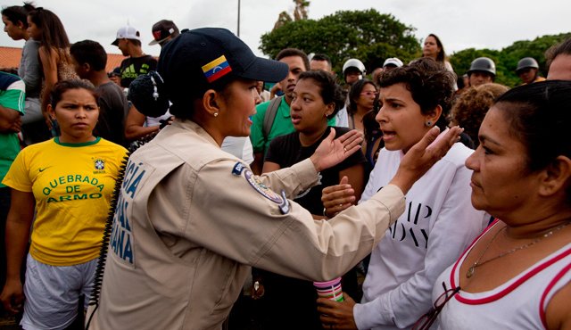Una mujer policía habla con una multitud enfurecida durante una manifestación por falta de alimentos en el vecindario Catia en Caracas, ocurrida este martes. AP