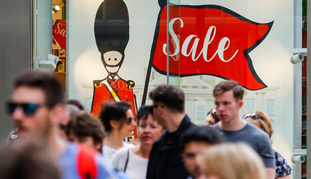 Los peatones caminan delante de una ilustración de un soldado de la Guardia de la Reina británica en el escaparate de una tienda en el centro de Londres. AFP