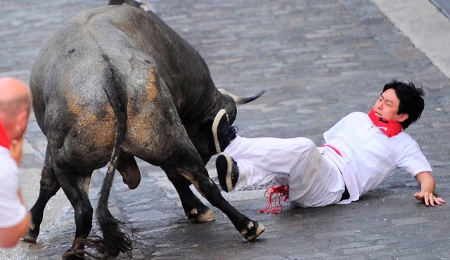 Un participante se encuentra en el suelo durante una de las corridas de toros, en el tercer día del festival encierro de San Fermín en Pamplona, norte de España. AFP