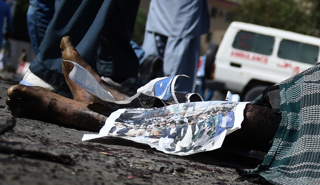 Manifestantes afganos se colocan cerca de los cuerpos de las víctimas en la escena del ataque suicida. Los yihadistas Estado Islámico se atribuyeron dos explosiones. AFP