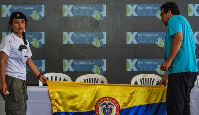 Miembros de las Farc ponen en la mesa una bandera de Colombia antes del anuncio de la aprobación de un acuerdo de paz con el gobierno durante la ceremonia de clausura de la Décima Conferencia Nacional Guerrillera. Colprensa