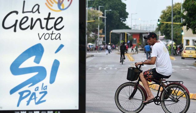 Un hombre montado en una bicicleta pasa cerca de un cartel que dice: “El pueblo vota sí a la paz” en una calle en Cartagena, ciudad donde hoy el presidente de Colombia Juan Manuel Santos y el líder de las Farc, Rodrigo Londoño ‘Timochenko’, firmarán oficialmente el acuerdo de paz alcanzado el 24 de agosto en La Habana, Cuba. AFP