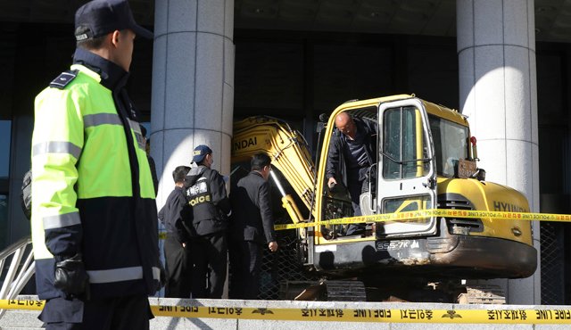 Policías examinan una excavadora luego que un hombre arremetiese con ella contra una puerta cerca de la Fiscalía de Seúl. Las autoridades arrestaron al sujeto. AP