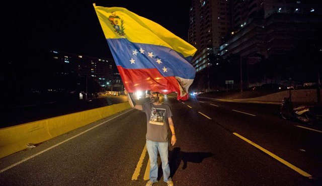 Un dirigente opositor agita una bandera venezolana durante una protesta contra el presidente Nicolás Maduro en Caracas. AP