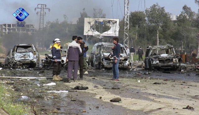 En la imagen tomada de un video proporcionado por la Agencia de Noticias Thiqa, rebeldes armados se encuentran en el lugar donde se registró una explosión que causó daños a varios autobuses y camionetas en el áreea de Rashideen, AP