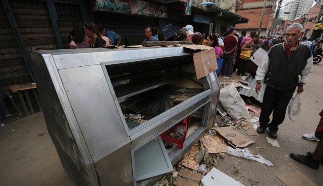Un peatón pasa junto a un refrigerador destruido durante un saqueo la noche del viernes en el barrio El Valle en Caracas, Venezuela. AP