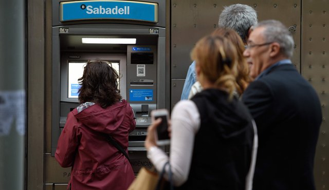 Independentistas catalanes esperaron fuera del cajero automático de CaixaBank, en una gran avenida de Barcelona. AFP