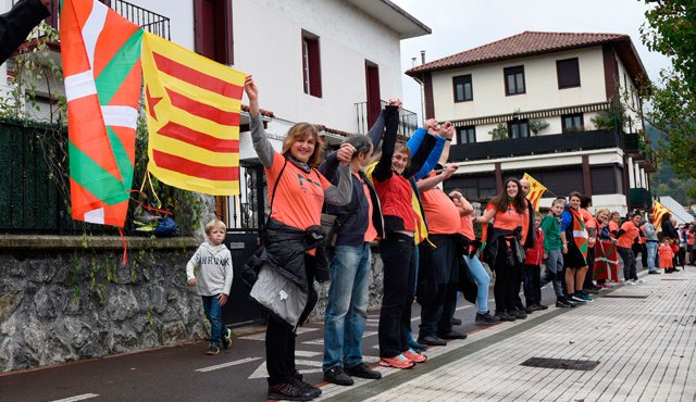 La gente sostiene banderas catalanas independentistas catalanas y banderas del País Vasco cuando participan en una cadena humana entre aldeas en el pueblo vasco norteño de Lazkao AFP