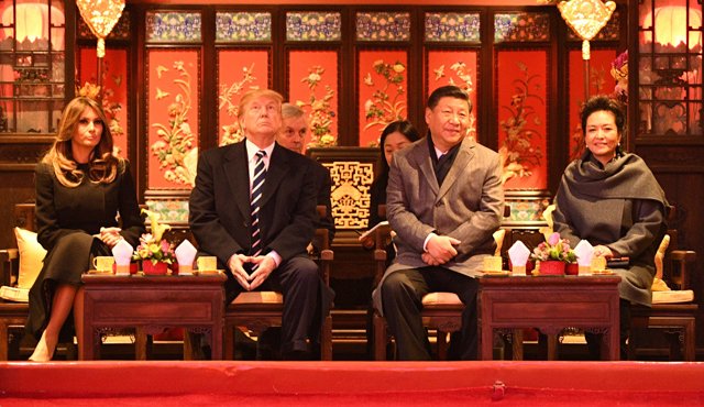 El presidente Donald Trump (izquierda) levanta la vista mientras se sienta junto a la Primera Dama Melania Trump y Xi Jinping (derecha) y su esposa Peng Liyuan. AFP
