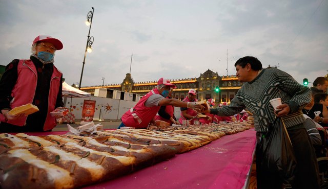 La gente se reúne en la plaza Zócalo en la Ciudad de México para obtener una pieza de la tradicional 'Rosca de Reyes' en la víspera de la Epifanía. AFP