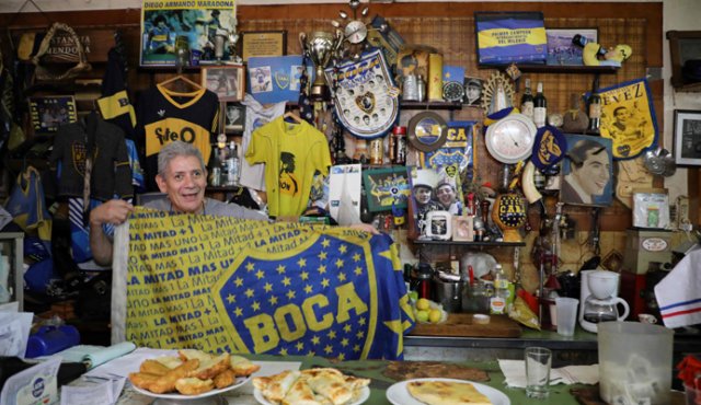 Un hincha sostiene una bandera de Boca Juniors en el restaurante Ribera Sur, en el barrio de La Boca en Buenos Aires. AFP