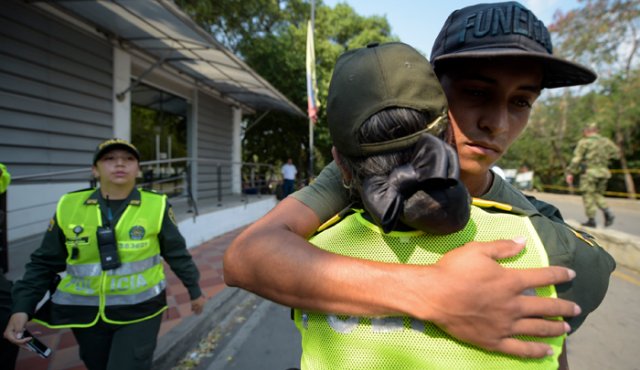 Un policía colombiano abraza a un miembro de las Fuerzas Armadas de Venezuela que desertó a este país. AFP