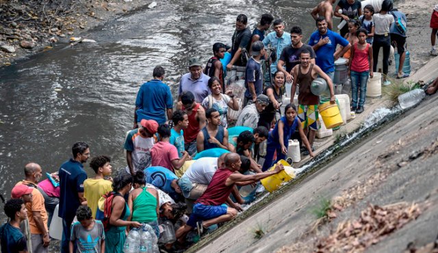 Miles de venezolanos, en medio de la desesperación y la angustia por la falta de agua, acuden a los contaminados ríos para recoger el líquido y enfrentar así la tremenda falta de los últimos días. AFP