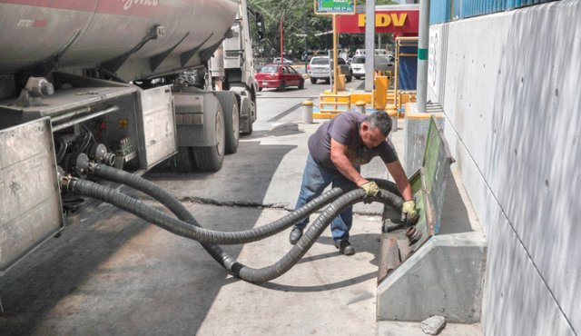 En Caracas, un trabajador prepara las mangueras de un camión cisterna para llenar tanques de combustible, ayer, en una estación de servicio que, al igual que las restantes, muestra largas filas de vehículos esperando abastecerse de gasolina. EFE