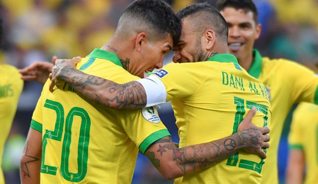 Dani Alves celebra con su compañero Roberto Firmino luego de anotar contra Perú. AFP