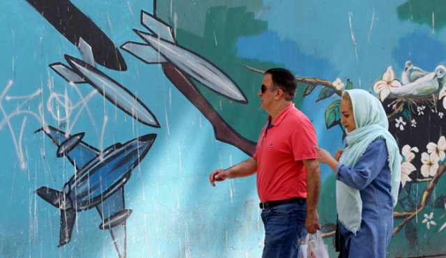 Una mujer pasa junto a una pintura mural a lo largo de la pared de la antigua embajada de Estados Unidos en la capital iraní de Teherán. AFP