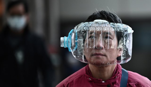 Una mujer usa una botella de agua de plástico con un recorte para cubrirse la cara, mientras camina por una pasarela en Hong Kong, el 31 de enero de 2020, como medida preventiva ante el coronavirus. AFP