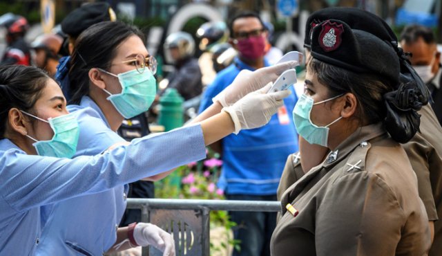 Funcionarios de salud, usando máscaras faciales en medio de temores sobre la propagación del nuevo coronavirus, controlan la temperatura corporal de las mujeres policías antes de una manifestación antigubernamental en Bangkok.
AFP