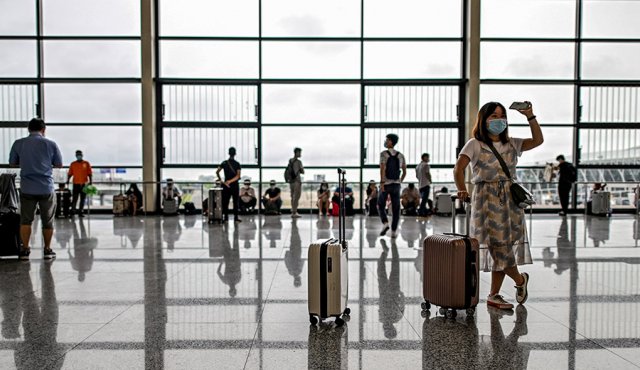 Los pasajeros que llevan máscaras faciales caminan por una sala siguiendo procedimientos preventivos contra la propagación del coronavirus en el aeropuerto internacional de Pudong en Shanghai. AFP
