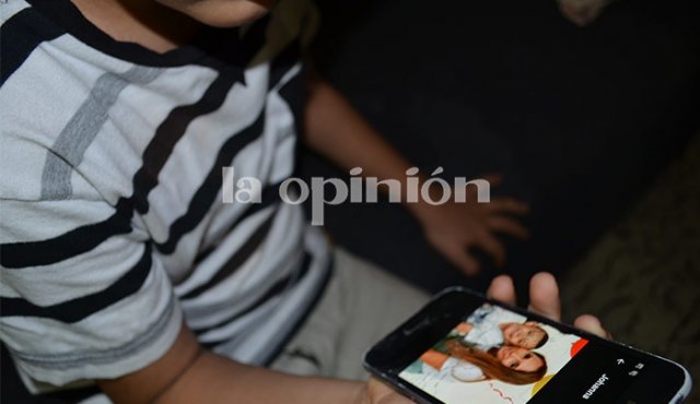 El pequeño Gabriel mira una foto de su mama en el celular de la abuela y le pide que regrese pronto.
Laura Serrano/La Opinión