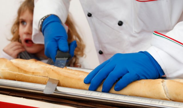 La baguette fue cortada y untada con Nutella, para ser distribuida entre cientos de asistentes. AP