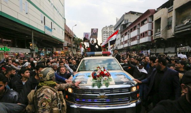 Los iraquíes rodean el coche que transporta los ataúdes del poderoso general iraní Qasem Soleimani y del hombre iraní en Irak, Abu Mehdi al Muhandis, muerto en una incursión estadounidense, en su funeral en el barrio de Kazimiya, Bagdad, el 4 de enero de 2020. AFP