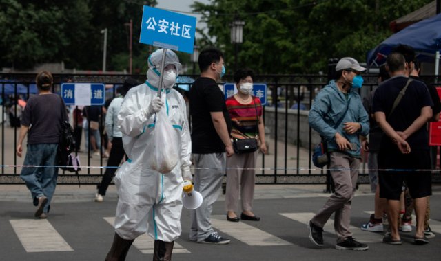 Personal médico en China levanta un cartel para ayudar a las personas que viven cerca o que han visitado el mercado Xinfadi, donde surgió un nuevo brote de coronavirus. AFP