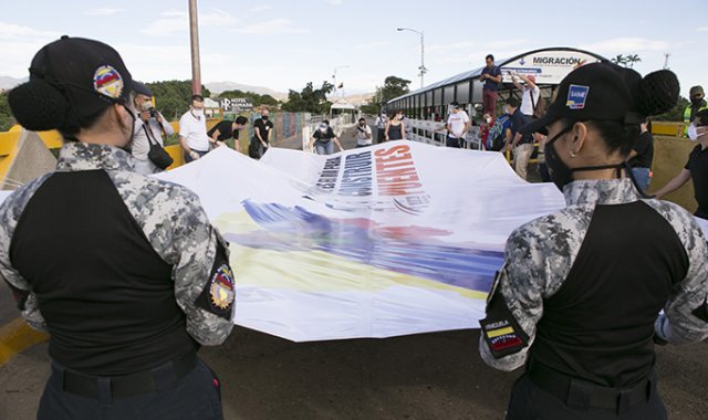 Del lado venezolano, dos funcionarias de la Policía Migratoria sostuvieron la pancarta gigante una vez se abrió el puente, en apoyo a la iniciativa mundial. Juan Pablo Cohen / La Opinión